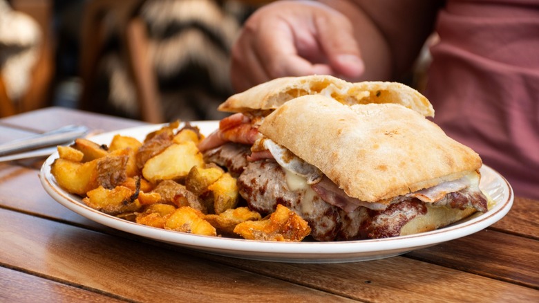 Typical chivito sandwich from Uruguay served with rustic potatoes
