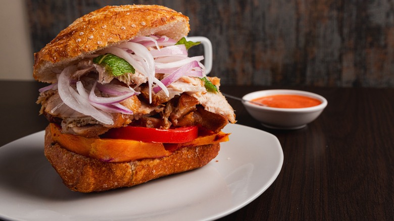 traditional peruvian breakfast made of fried pork, salad in a bread, called "pan con chicharron"