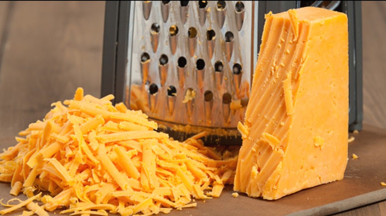 A block of Red Leicester cheese (actually orange), shredded.