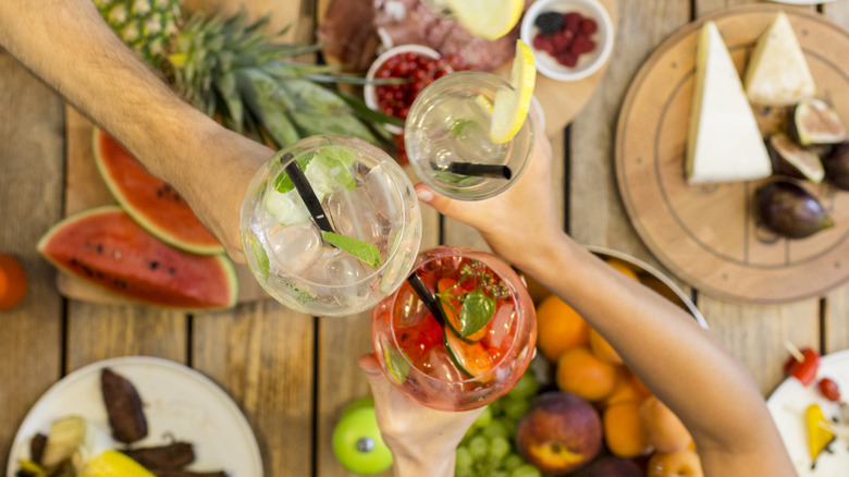 Friends toasting with assorted cold drinks while dining outdoors