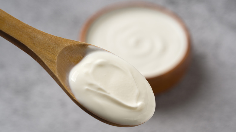 Wood spoon with thick white sauce with bowl in background