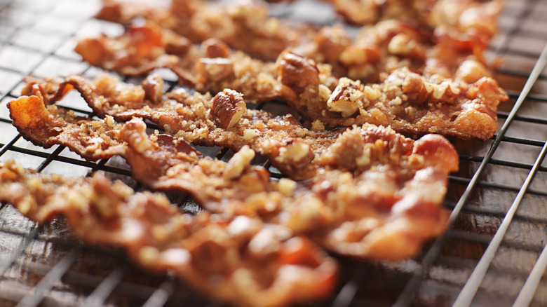 Candied bacon on a cooling rack with brown sugar and nuts
