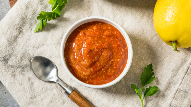 cocktail sauce in ramekin on cloth napkin with spoon and lemon