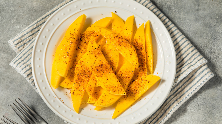 fresh mango slices on plate with Tajín