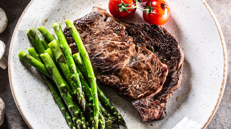 Steak on a plate with roasted asparagus and tomatoes