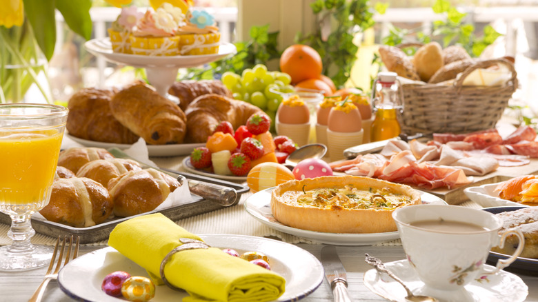 An Easter brunch with frittata, coffee, festive napkins, orange juice, cupcakes, and croissants