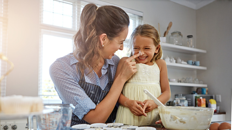A woman and young girl smiling together in the kitchen