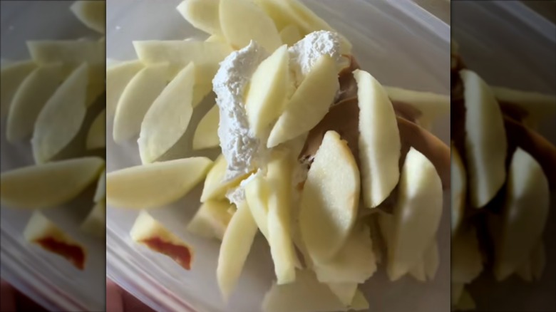 Sliced apples on top of peanut butter and Cool Whip in a plastic container