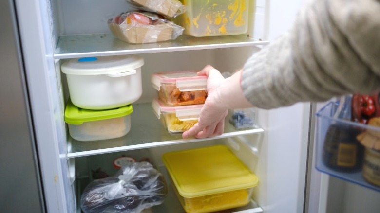 a man places cooked leftovers in the refrigerator