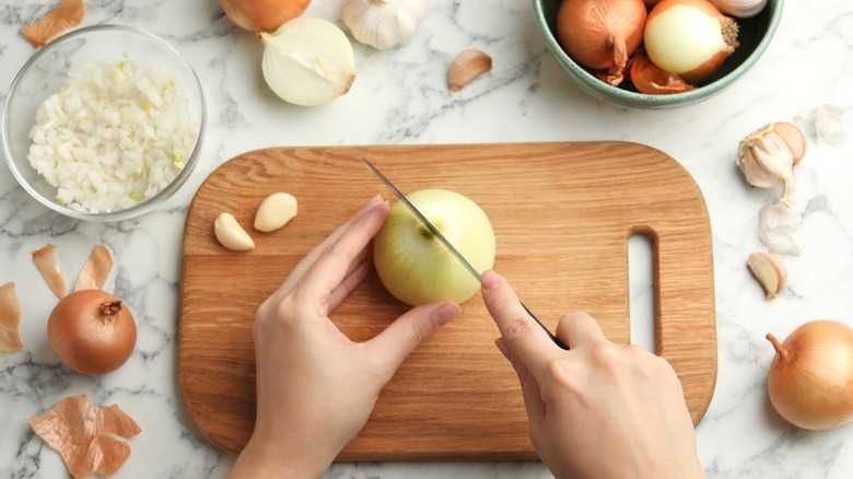 a woman chops onions on a cutting board