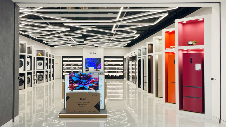 Haier electronics store entrance in contemporary shopping center featuring colorful refrigerators and washing machines