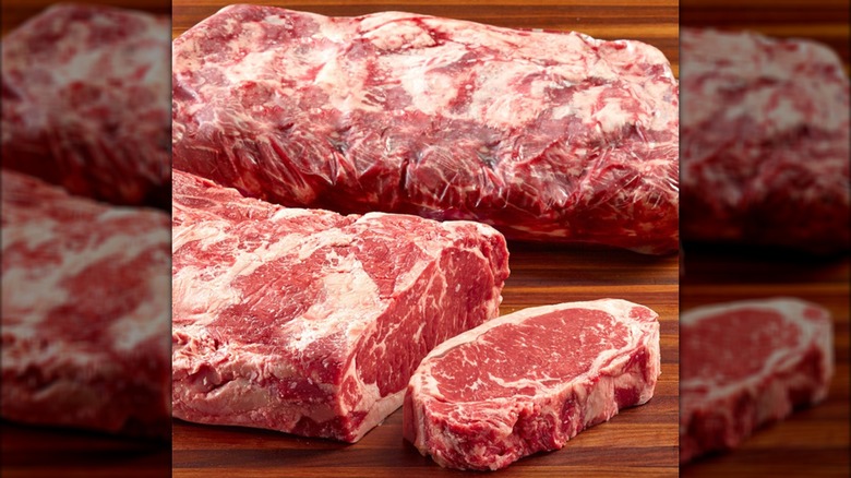 The prime strip loin with one strip steak cut off of it on a wooden surface from Costco