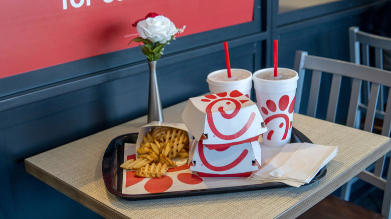 Chick-fil-A food on table with drinks and fries and decorated flowers.