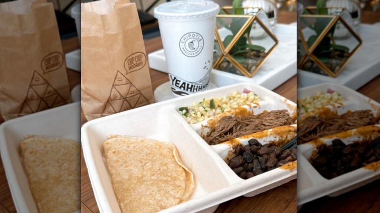 Chipotle kids meal with tortillas, black beans, corn, meat, side of chips, and a drink