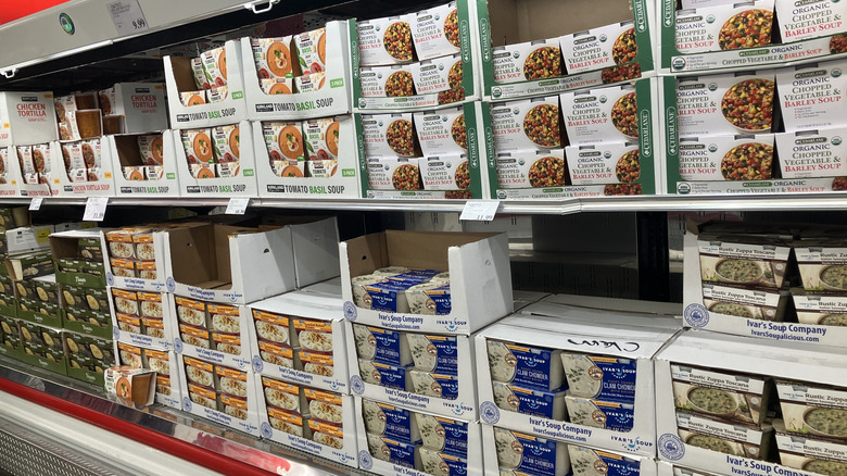 several soups are shown lined up on refrigerated shelves at Cosco, including clam chowder and vegetable barley soups