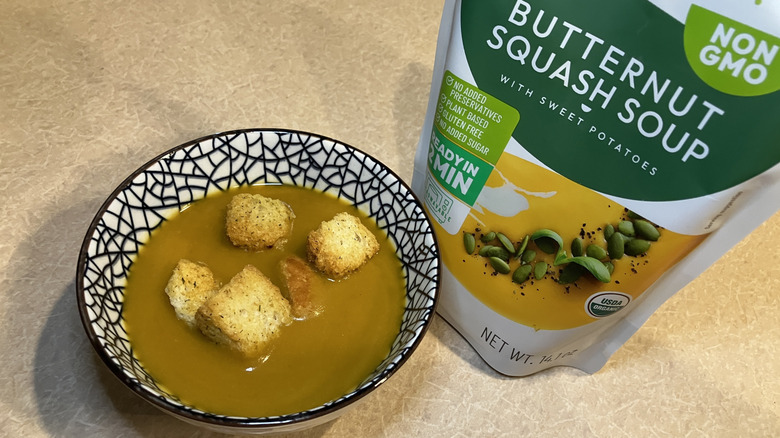 bowl of squash soup with seasoned croutons next to the pouch the soup came in