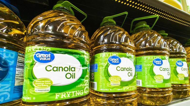 Large bottles of Great Value canola oil line a shelf.
