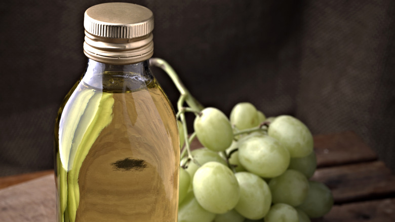 Close-up of a bottle of grapeseed oil with grapes in the background