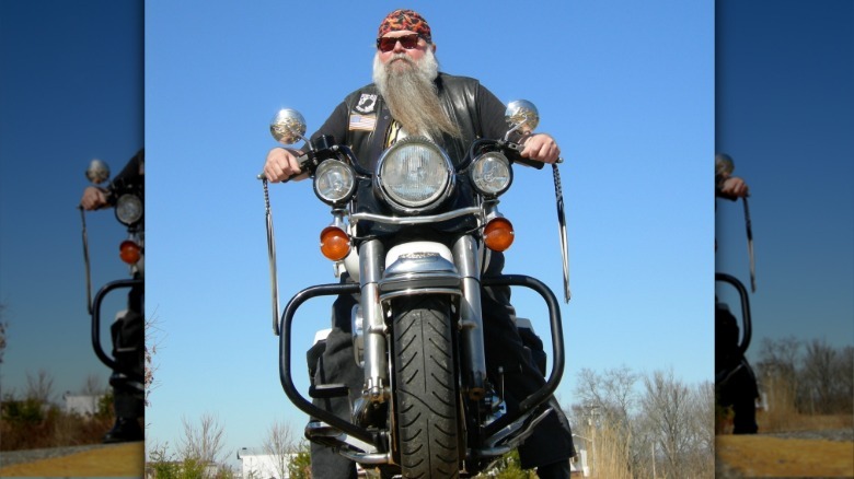 Biker Billy sitting on top of a police Harley-Davidson motorcycle with a long beard and sunglasses.