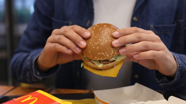 A person holding a McDonald's hamburger.