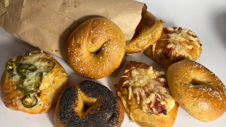 Assorted bagels spilling from brown paper bag including Poppyseed, jalapeño and others at Pipsqueak Bagels