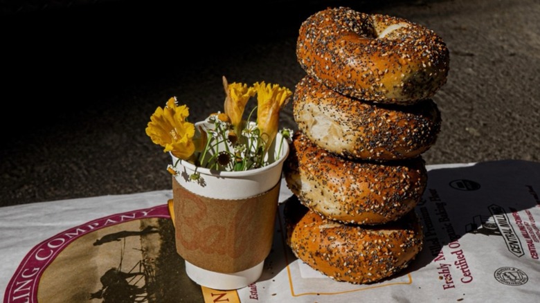 stack of everything bagels from Baby's Bagels beside a cup of yellow flowers on farmers market stand