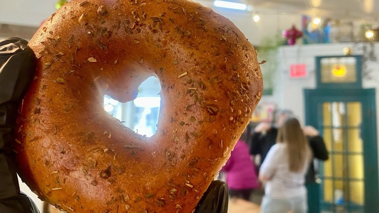 Close up of hand with bagel sprinkled with herbs at Wee Bird Bagel Cafe
