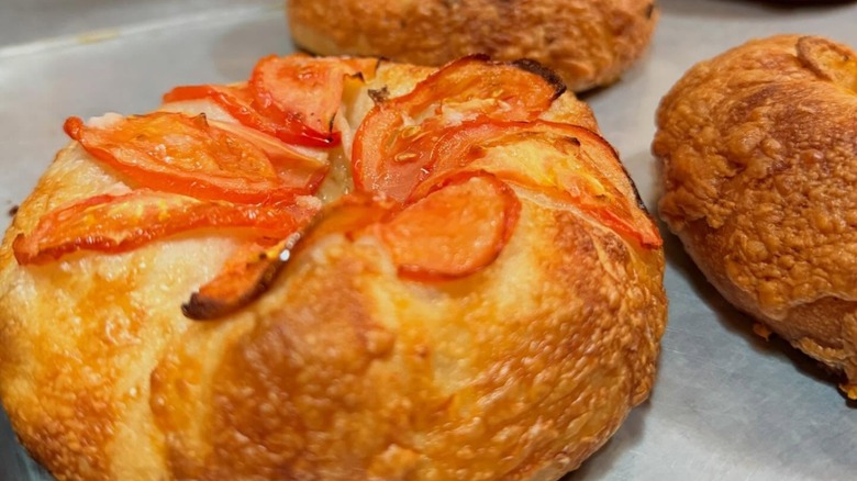 Bialy baked with tomato on top on baking sheet from Hey Bagel