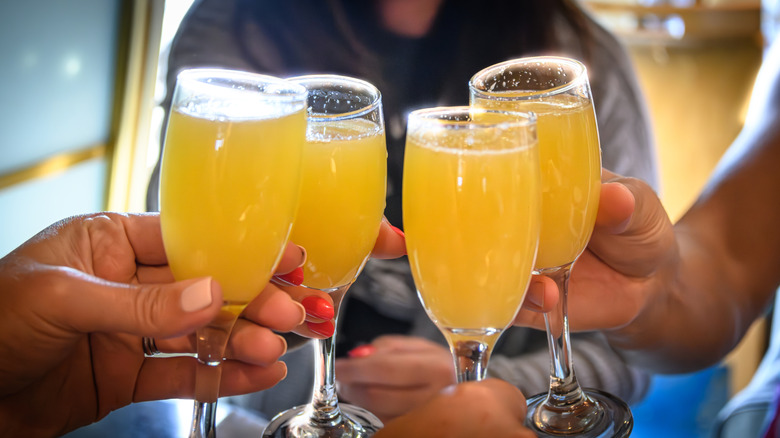 hands clinking mimosa glasses