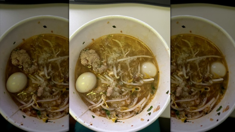 Khao piak khao or rice porridge with pork ribs and quail eggs in a white bowl