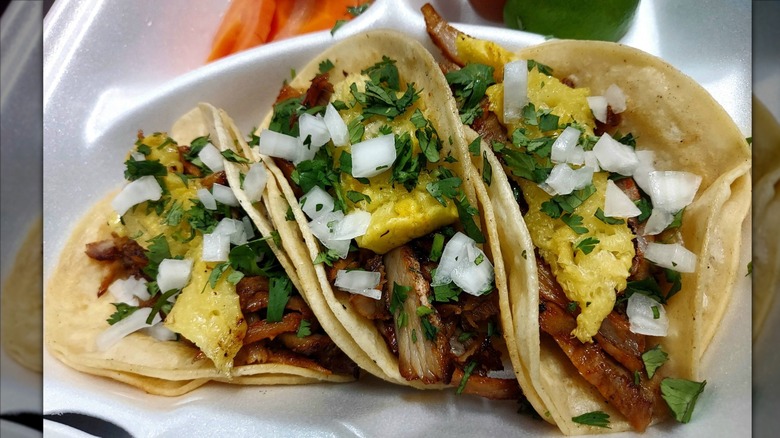 Three tacos al pastor with fresh onions and cilantro