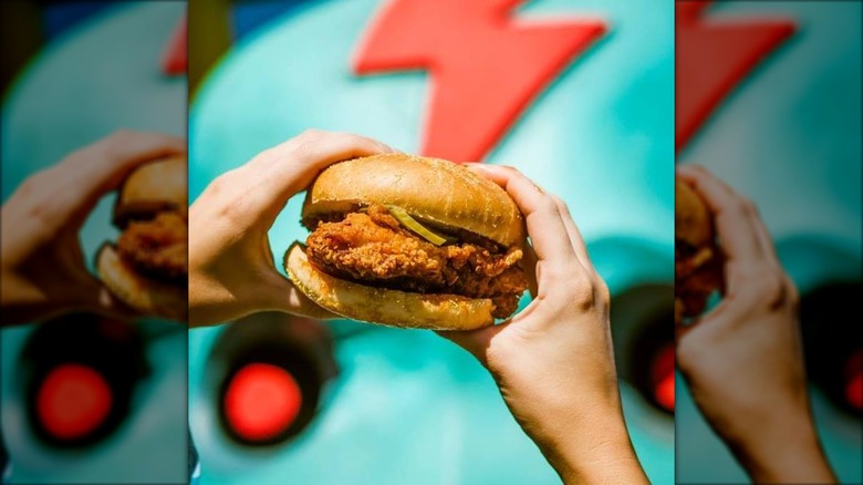 Person holding a fried chicken sandwich on a hearty bun