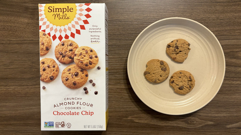 Simple Mills cookies sit on a plate next to their box.