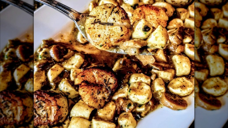 Fork lifts a scallop from plate of gnocchi and scallops from Semifreddo Italian Cuisine