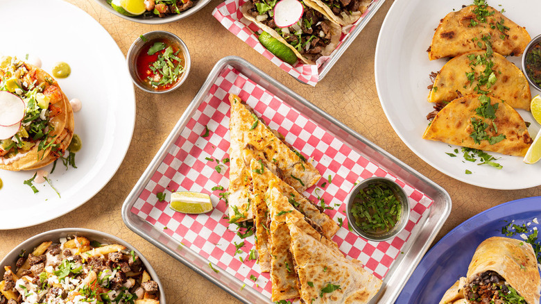 overhead shot of a table full of tacos, loaded fries, and other Mexican dishes from Flame the Taqueria