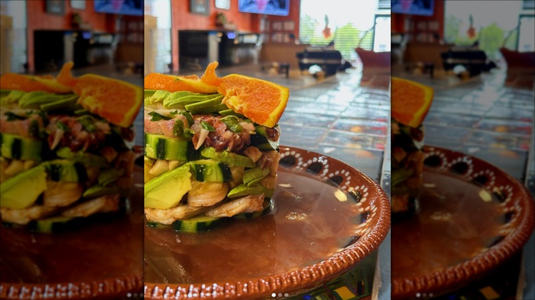 close up of a stacked seafood dish at El Chilango, dining room in the background