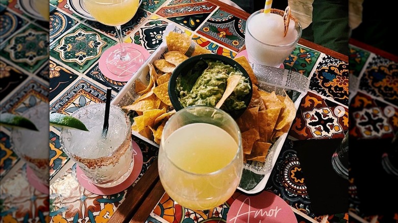 Chips, guacamole, and Mexican cocktails on the colorful, tiled table of Amor Loco