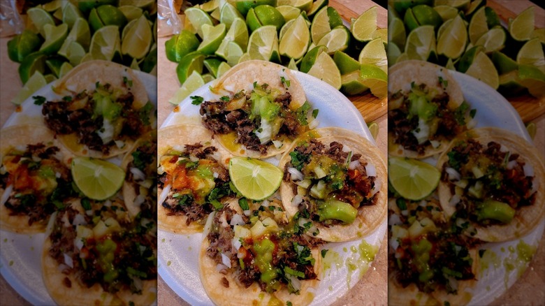 A casual plate of nachos next to a pile of lime wedges at Taco Revolution