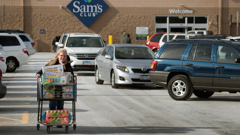 Woman in Sam's Club parking lot with cart filled with groceries