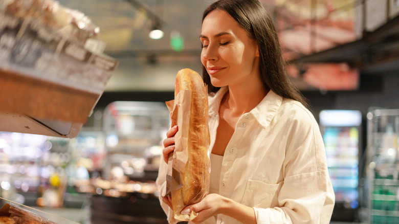 Woman sniffing a baguette with her eyes closed