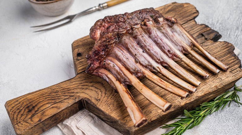 cooked rack of lamb on wooden board