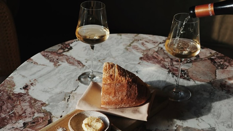 White wine being poured into wine glasses alongside bread and butter at Golden Age Wine