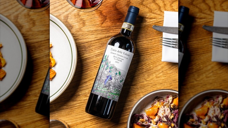 Bottle of Chianti wine laying on its side in between plates of food at Tavernetta
