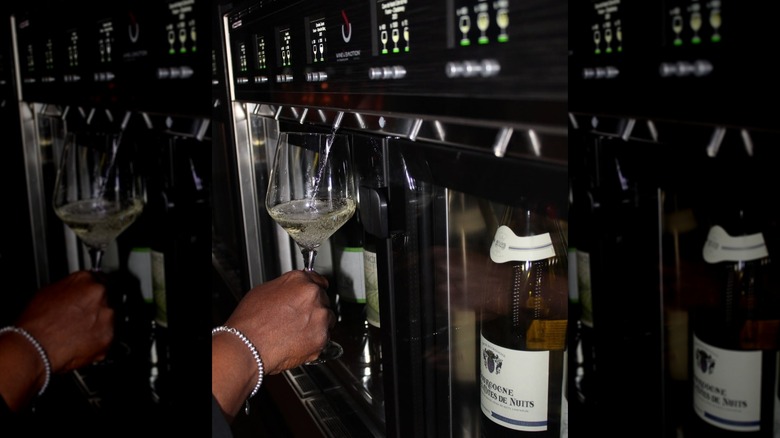 Hand holding wine glass as white wine is dispensed into it at The Sycamore Wine Bar