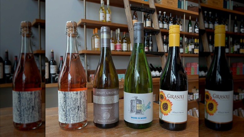 Four bottles of wine on a wooden counter with shelves of wine in the background