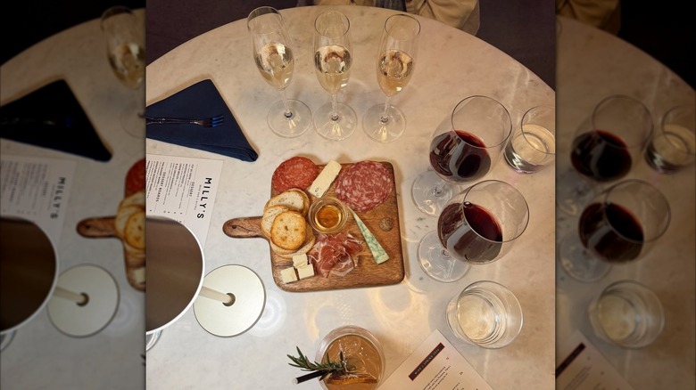 Top view of a table at Milly's wine bar, with a charcuterie board, flight of sparkling wines, and two glasses of red wine