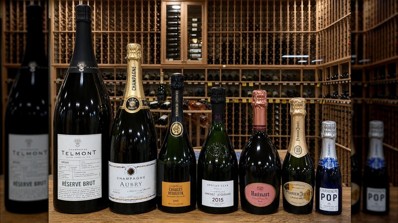 Bottles of Champagne in various sizes with wooden shelves of wine in the background at Khoury's Fine Wine and Spirits