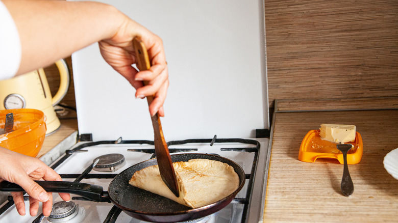 Someone in the kitchen flipping pancakes with a spatula