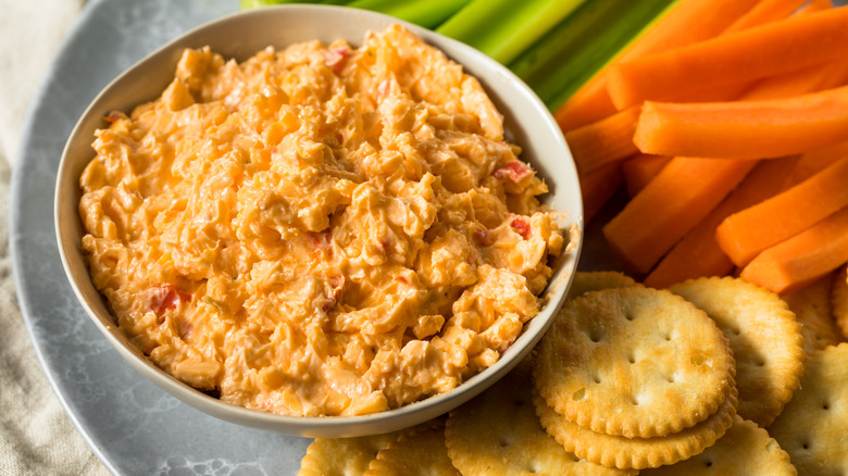 Dish of pimento cheese with crackers, carrots, celery
