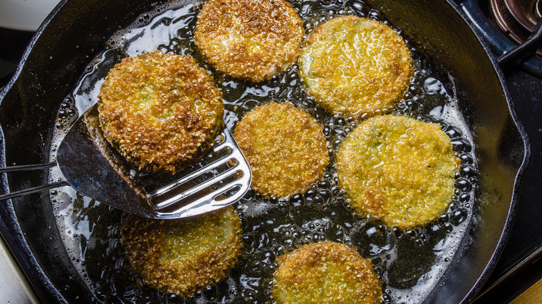 Spatula removing fried green tomato from cast iron skillet